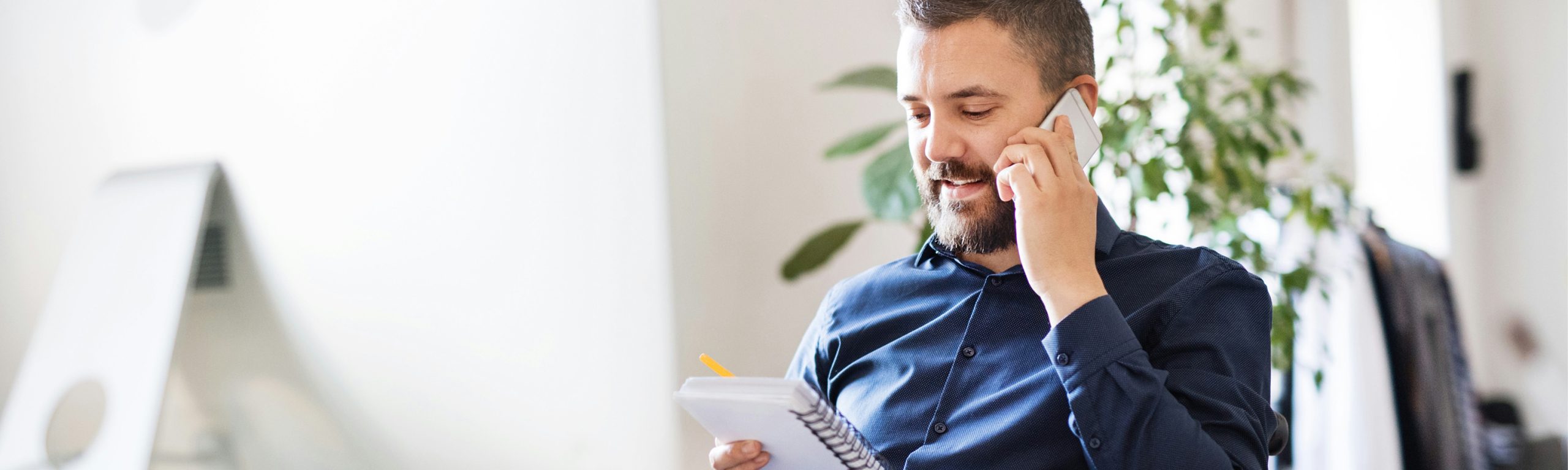 Bild eines Mitarbeiters der gerade telefoniert und in seine Notizen schaut.